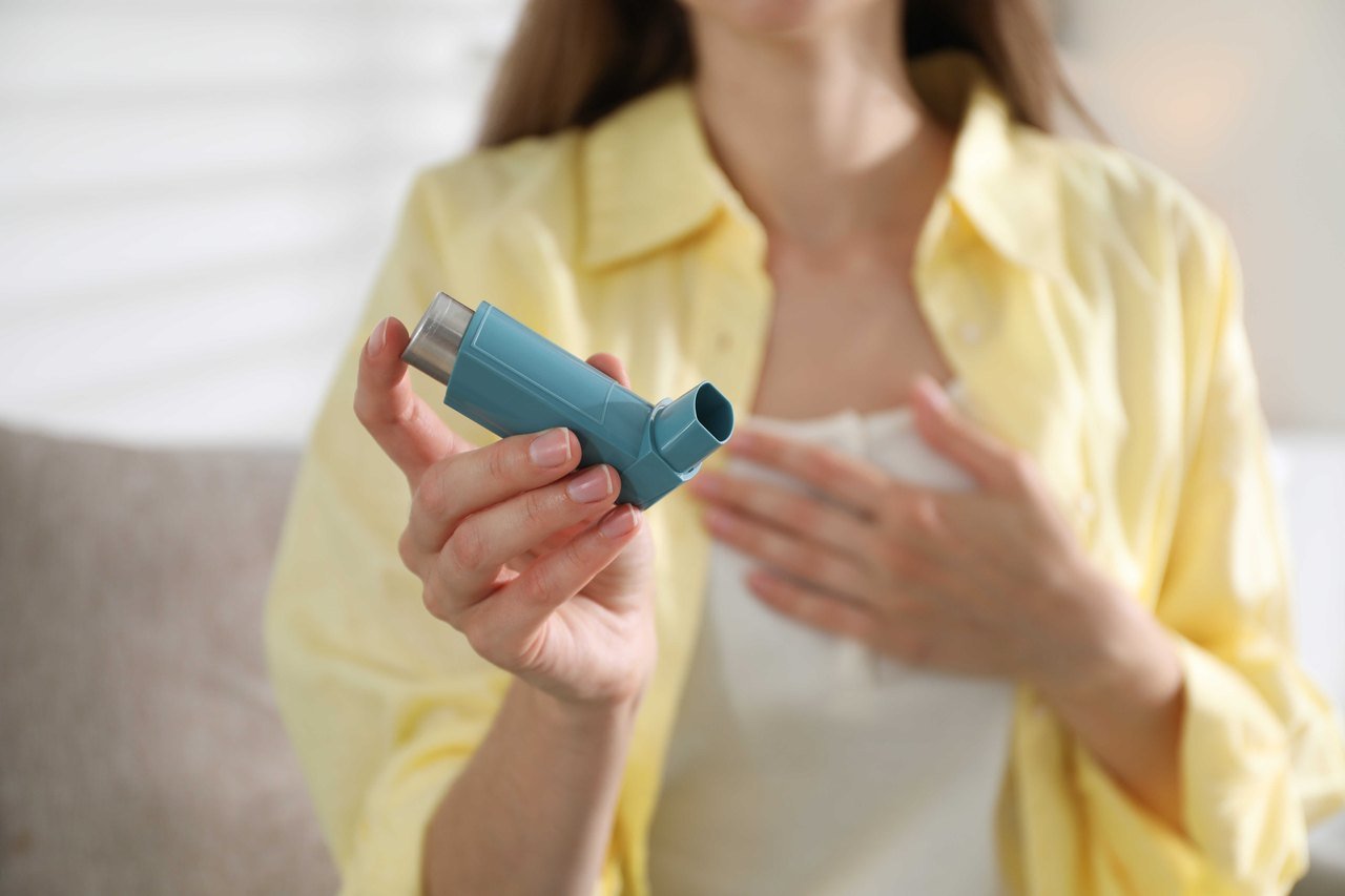 Woman holding an asthma inhaler at home