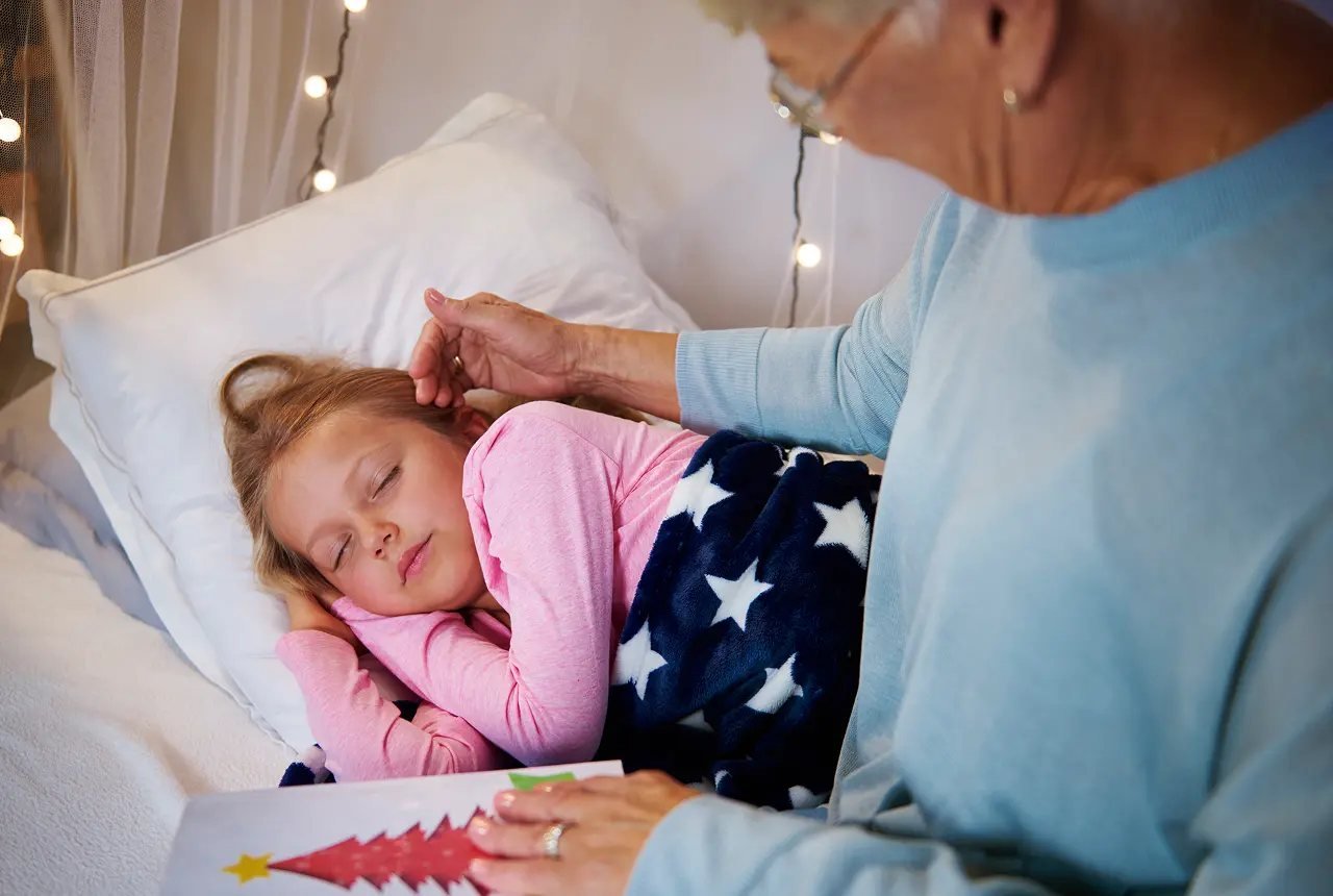 Young girl sleeping peacefully in bed at night while a parent checks on her