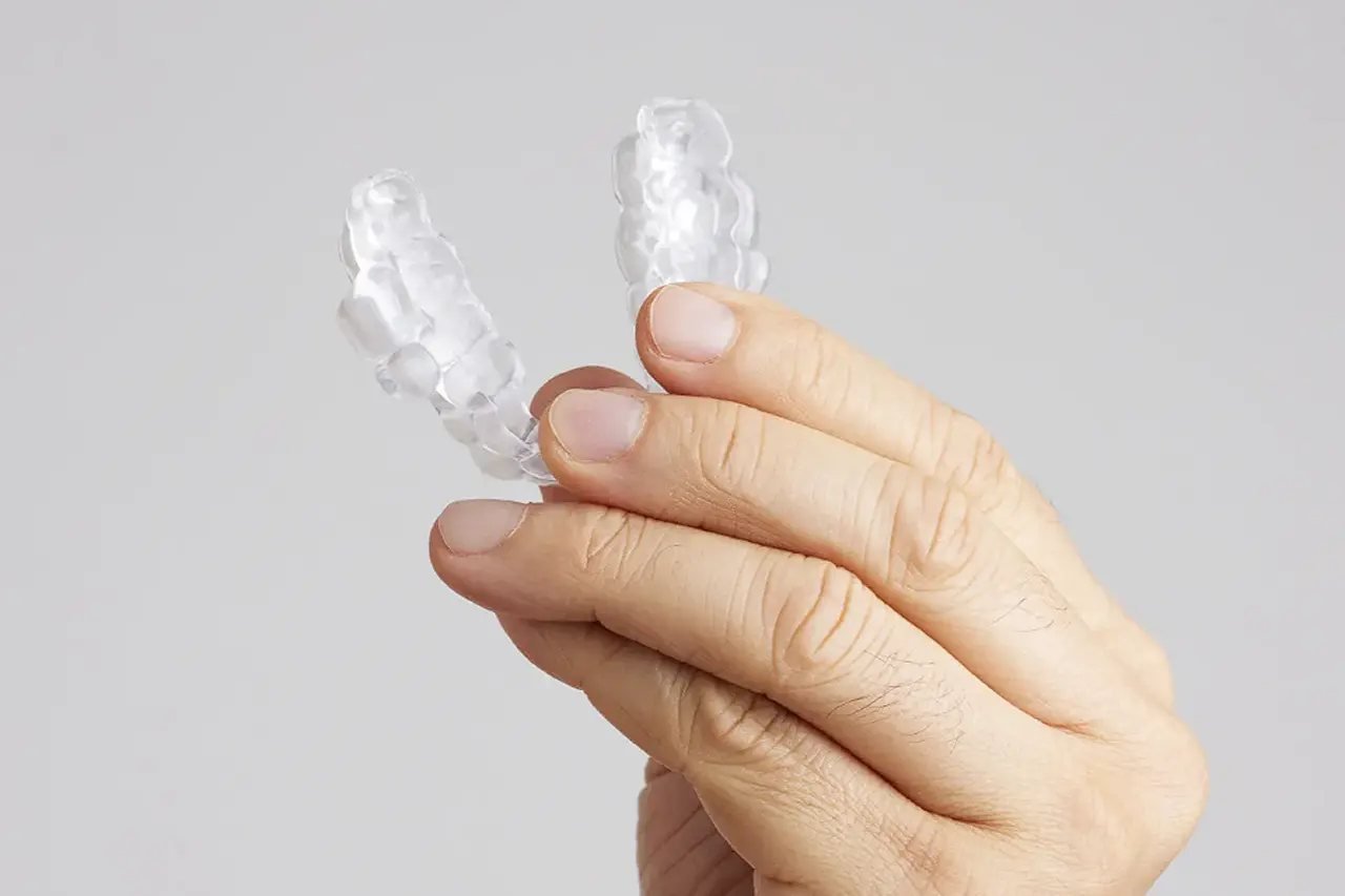 Hand holding a custom clear oral appliance, a comfortable CPAP alternative for sleep apnea