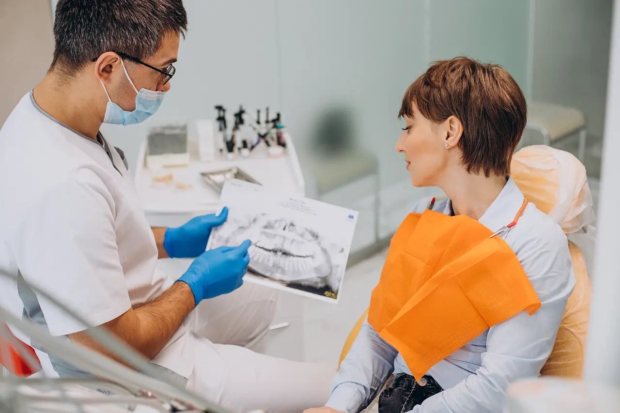 Dentist showing a jaw X-ray to an adult patient during a non-surgical palatal expansion consultation