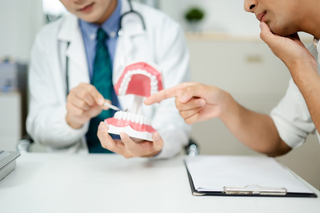 Provider pointing to a jaw model with a pen while a patient points to the teeth and asks a question