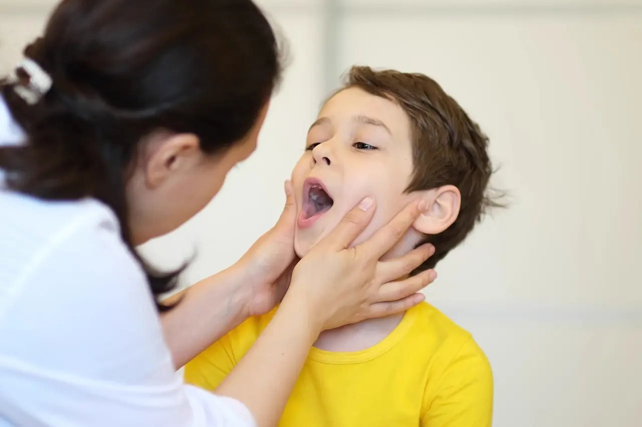 Pediatric dentist examining a child’s mouth and throat structure during a sleep apnea and airway evaluation