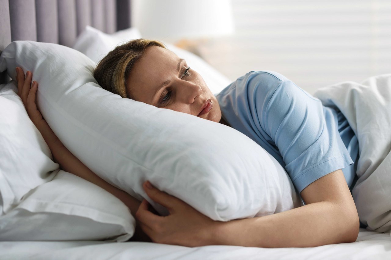 Woman lying awake in bed looking tired after a night of broken sleep
