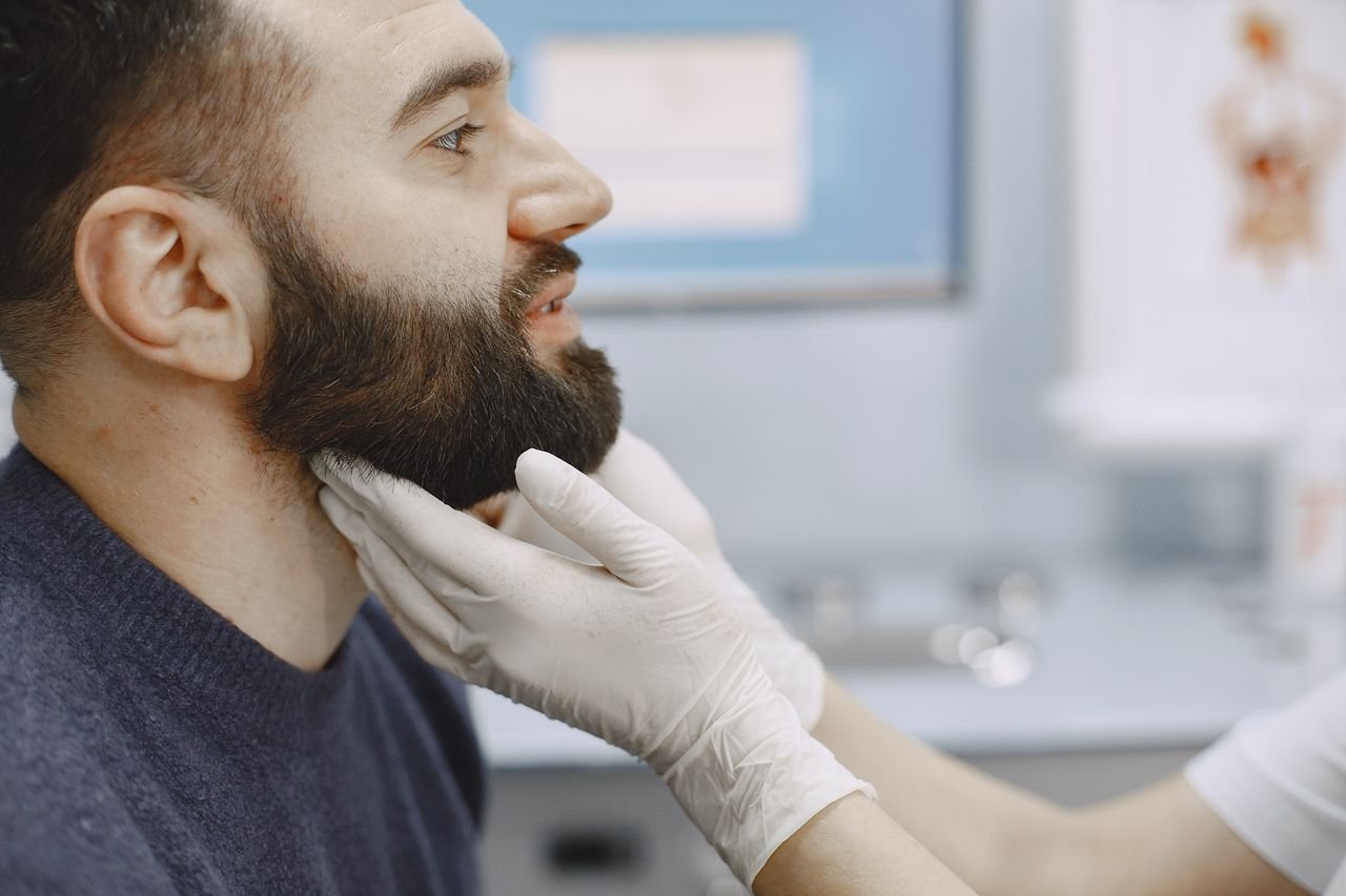 Provider examining a man's jaw and neck during an evaluation